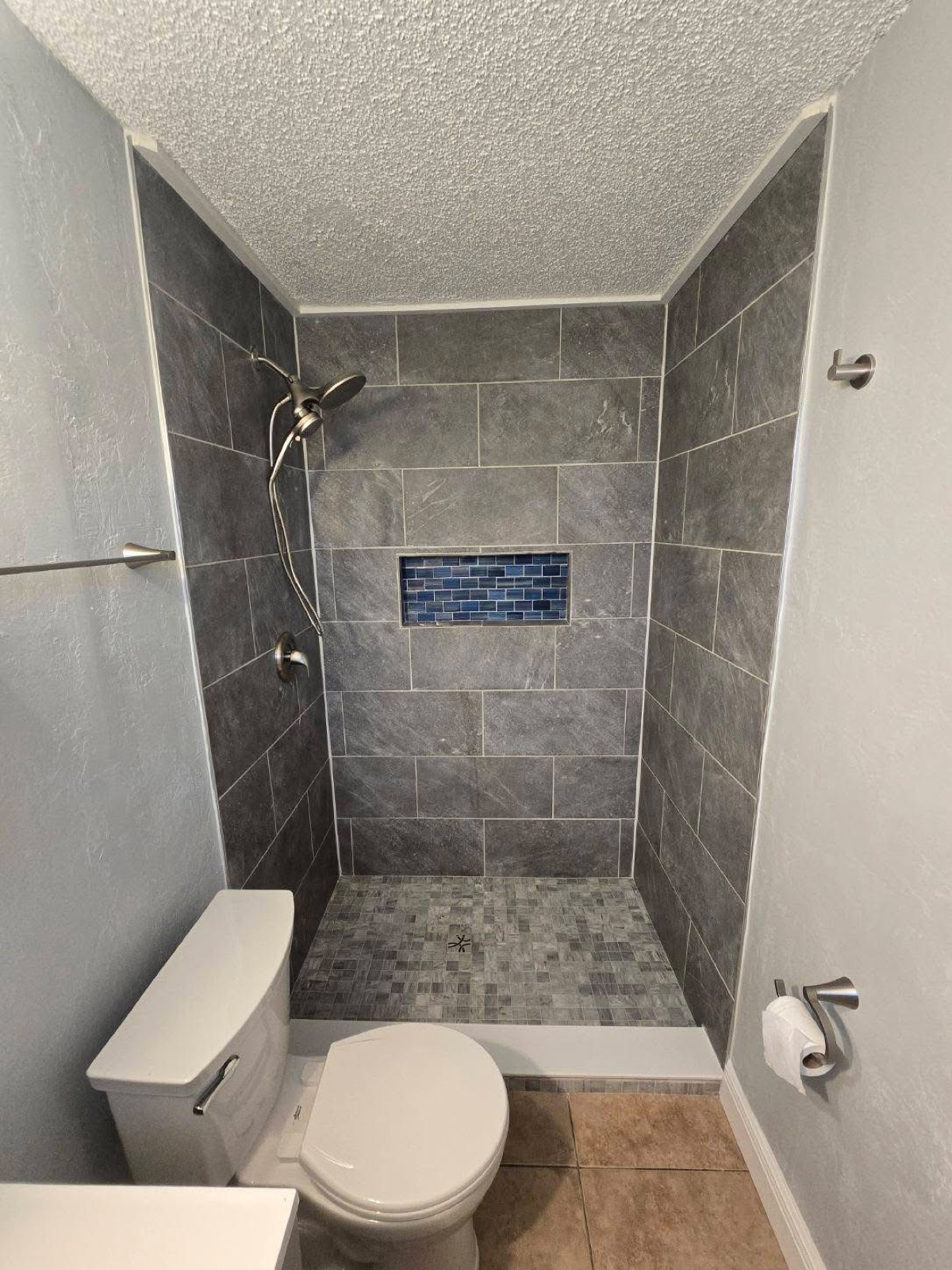Completed gray tile walk-in shower