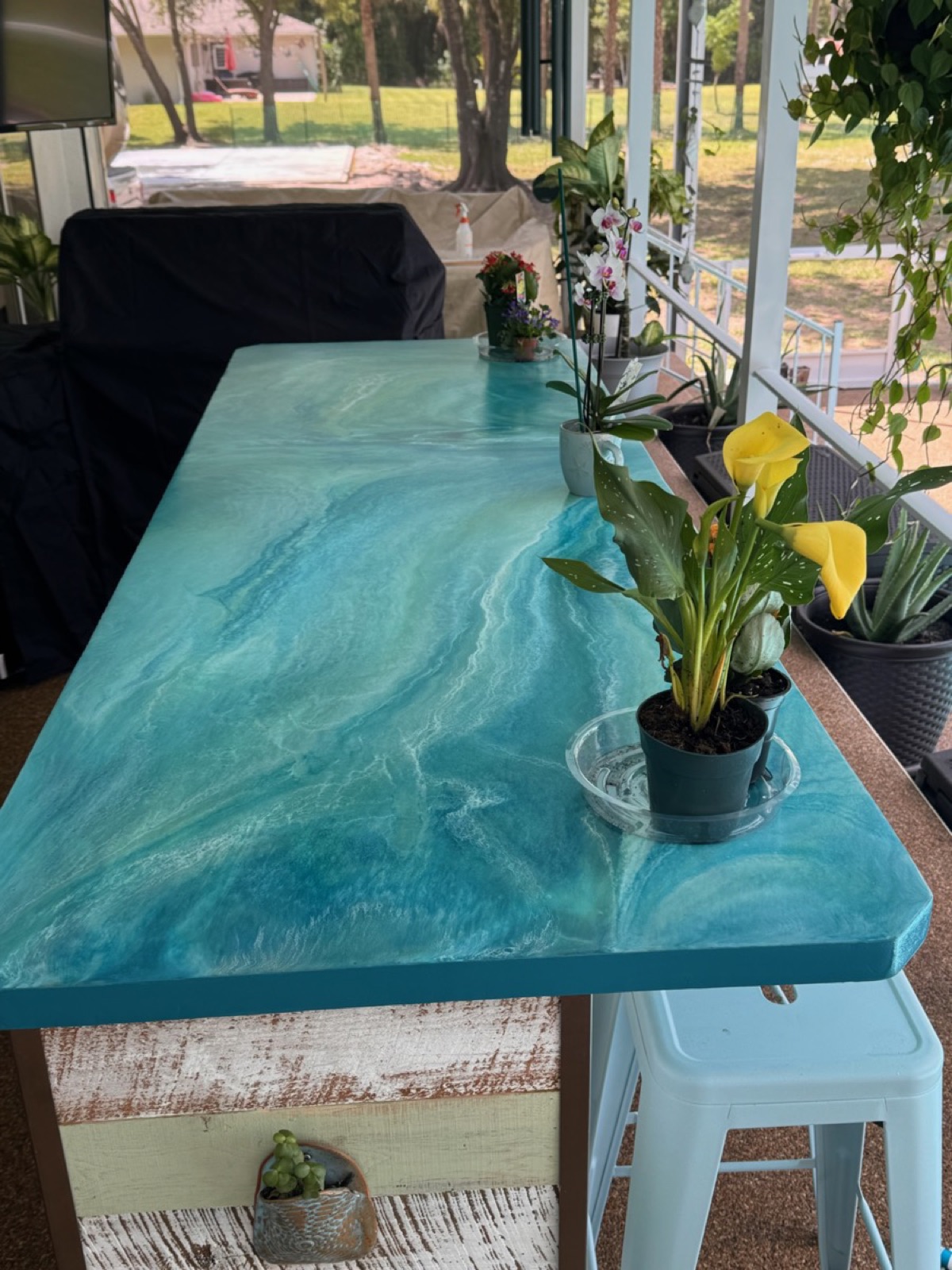 Custom epoxy resin countertop in ocean blue with swirling wave pattern on outdoor bar