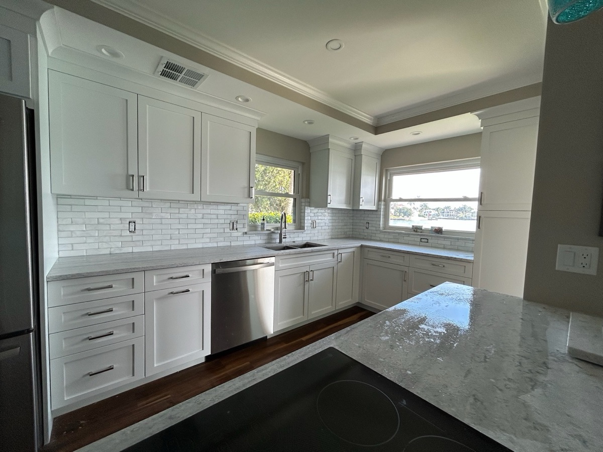 Kitchen cabinet and tile installation showing hood vent, wall tile, and granite countertops